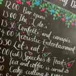 wedding sign in blackboard style showing the order of events at a summer wedding